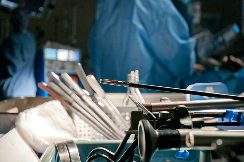 A laparoscopic tray with a fenestrated bowel grasper is in the foreground while a traditional open surgical tray lies in the background with a series of different grasping forceps. The most obvious difference between the two different instrument designs lies in the long thin shaft that is mandated for laparoscopic instrumentation. 