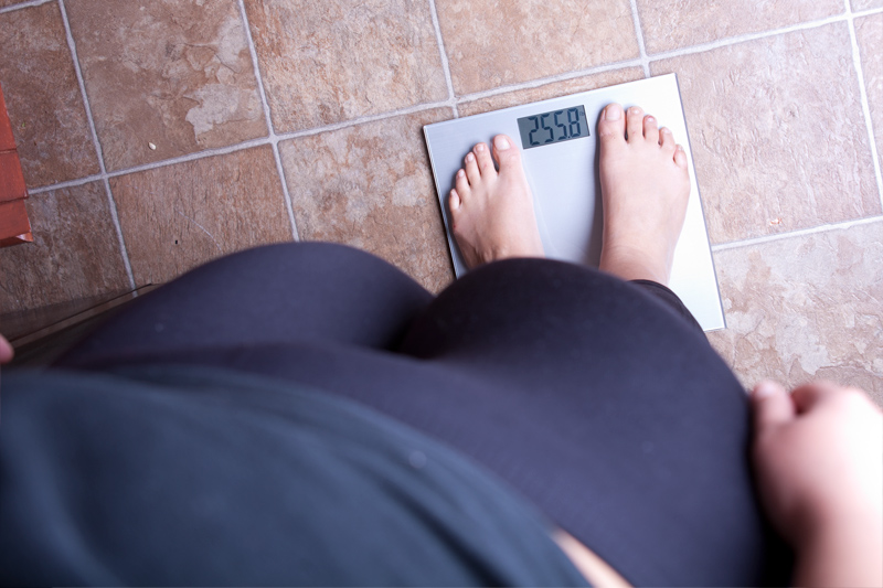 Obese person checking weight on scale